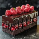 Gâteau truffe au chocolat noir, décoré de framboises fraîches sur une ganache brillante