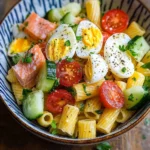 Gros plan sur les pâtes, morceaux de surimi, œufs durs en quartiers et légumes mélangés